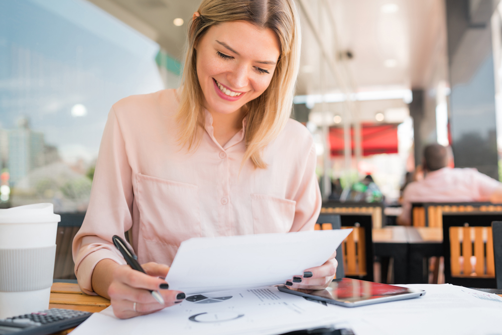 Young Business Woman working in coffee shop reviewing CRMBCs Self Insurance offerings and services